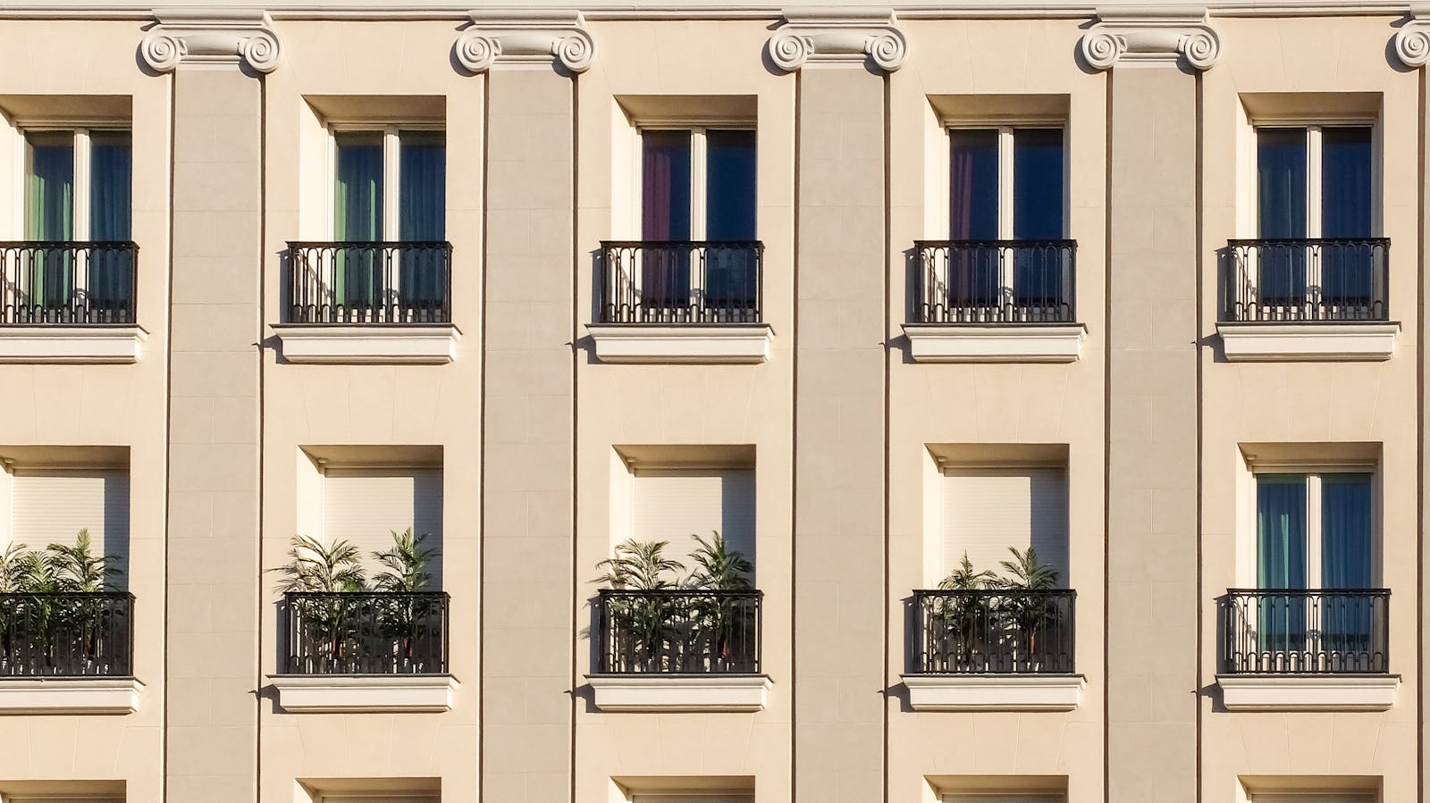 condo Elegant building exterior with classic windows and balconies adorned with plants.